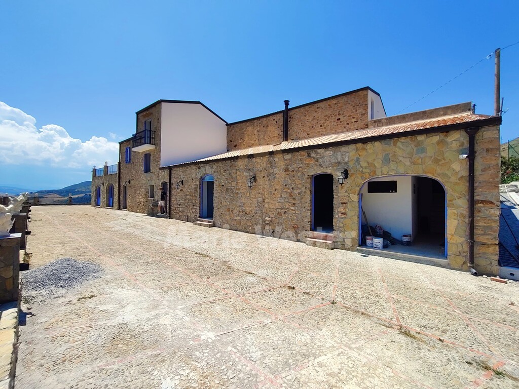 A stone courtyard with an open room and paint tins by the door