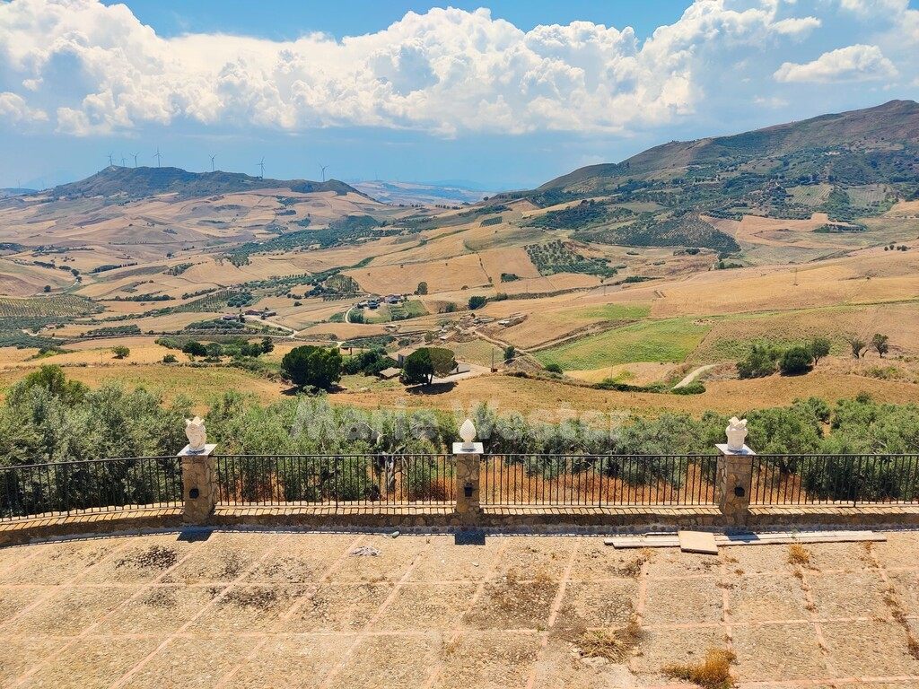 A terrace looking over dry hills, with wind turbines on a far ridge