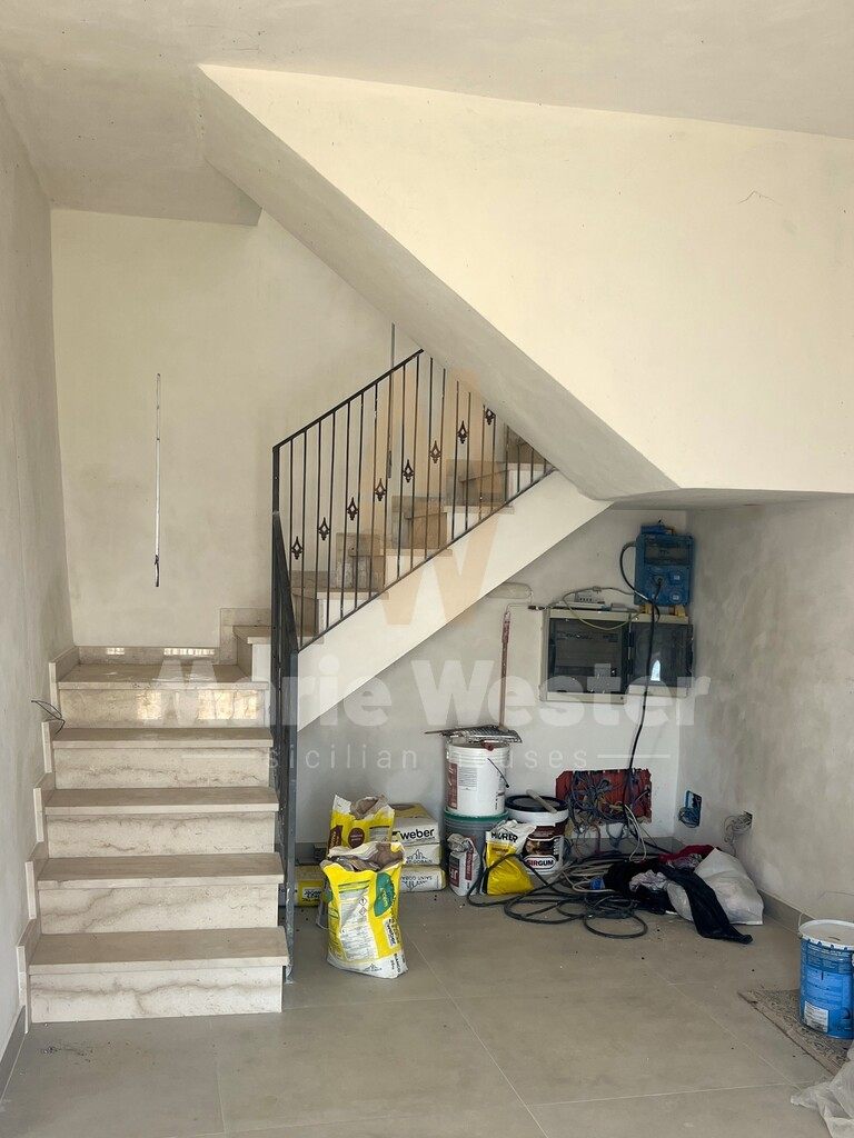 A marble stair with bags of plaster and an open electrical panel underneath