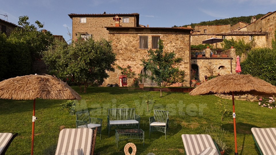 The lawn of the guesthouse with parasols, loungers, and the stone house behind