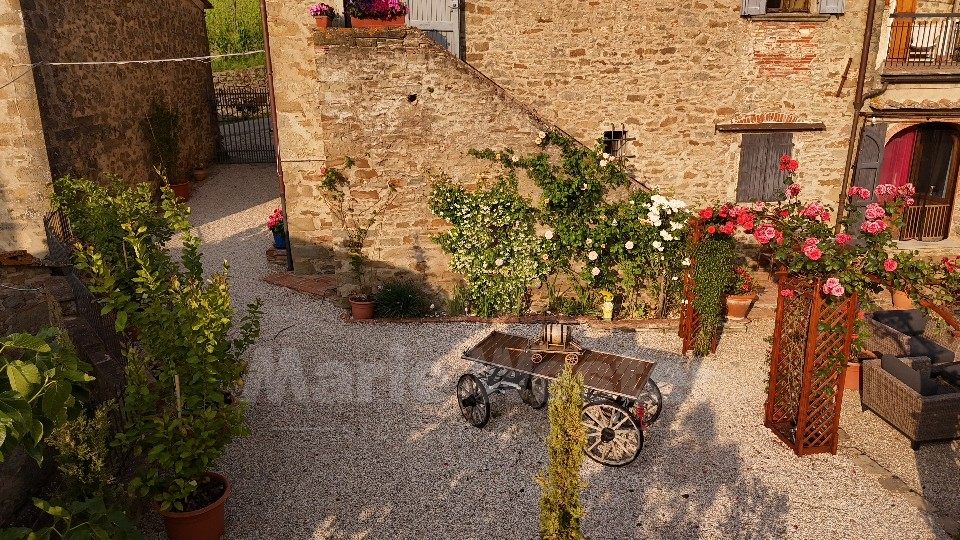 A gravel court with roses, stone walls, and a wooden cart used as a table