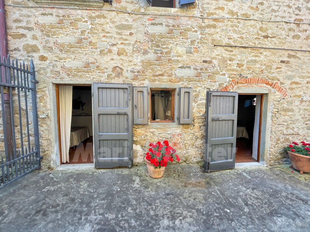 Two ground-floor doors with grey shutters open onto made beds