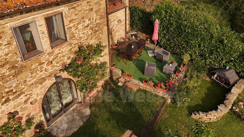 A lower garden with an arched glass door, roses, and a table on a green mat