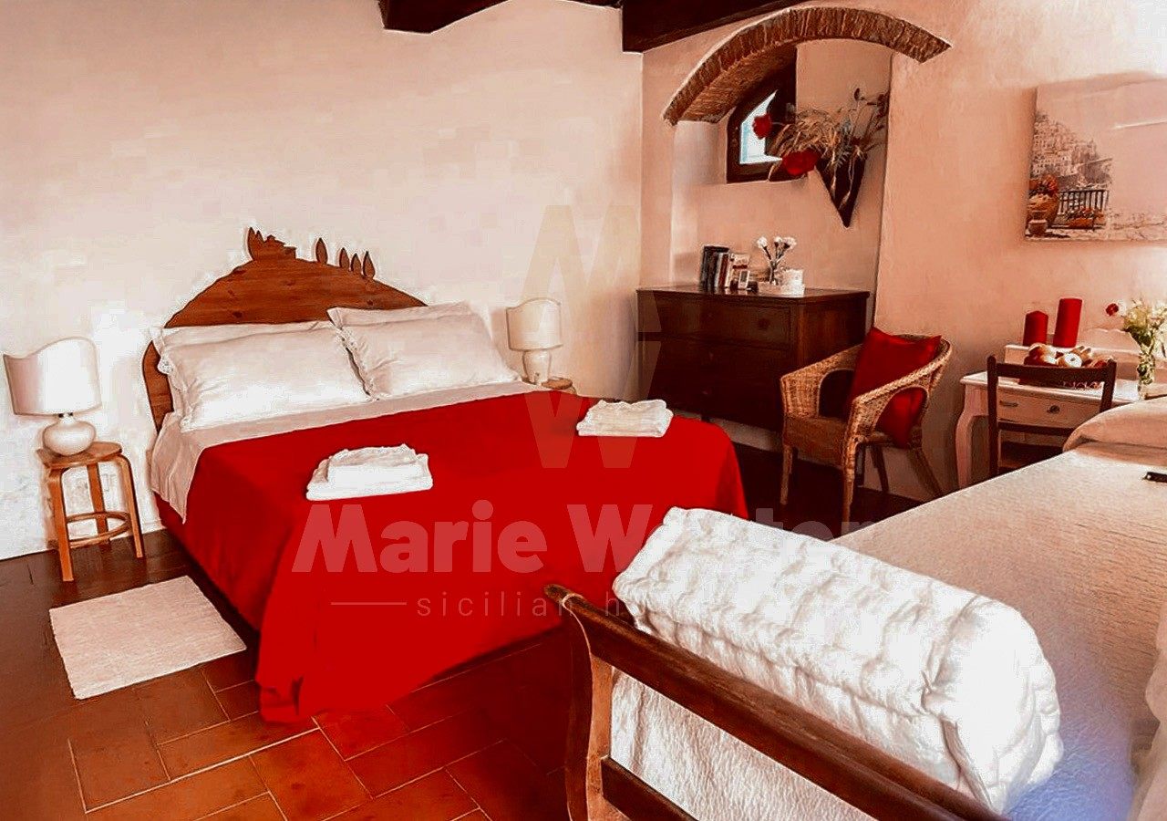 A guest bedroom with a red coverlet and folded towels