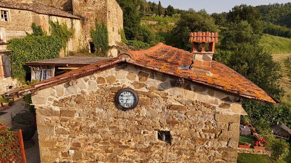 A rough stone annex with a round window and lichen on the roof tiles
