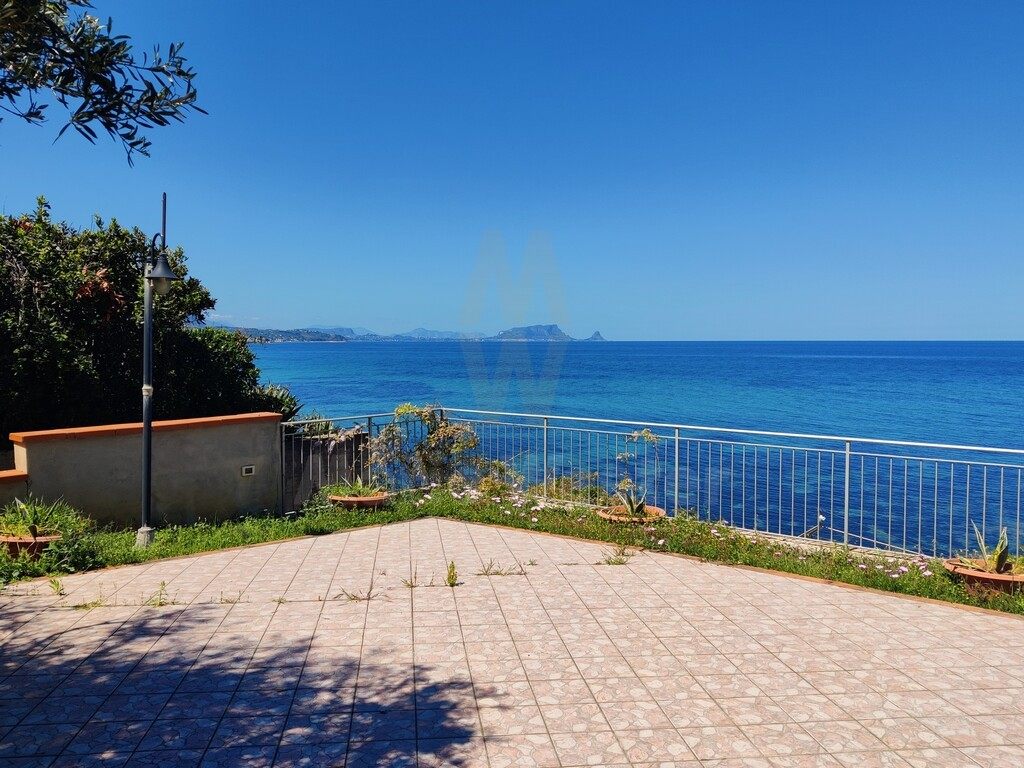 A paved terrace pointing at the open sea, with a metal rail along the edge