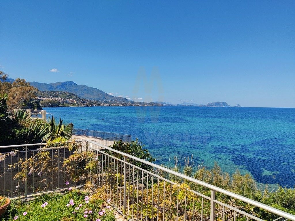 A terrace rail above clear blue water, with the coast and islands beyond