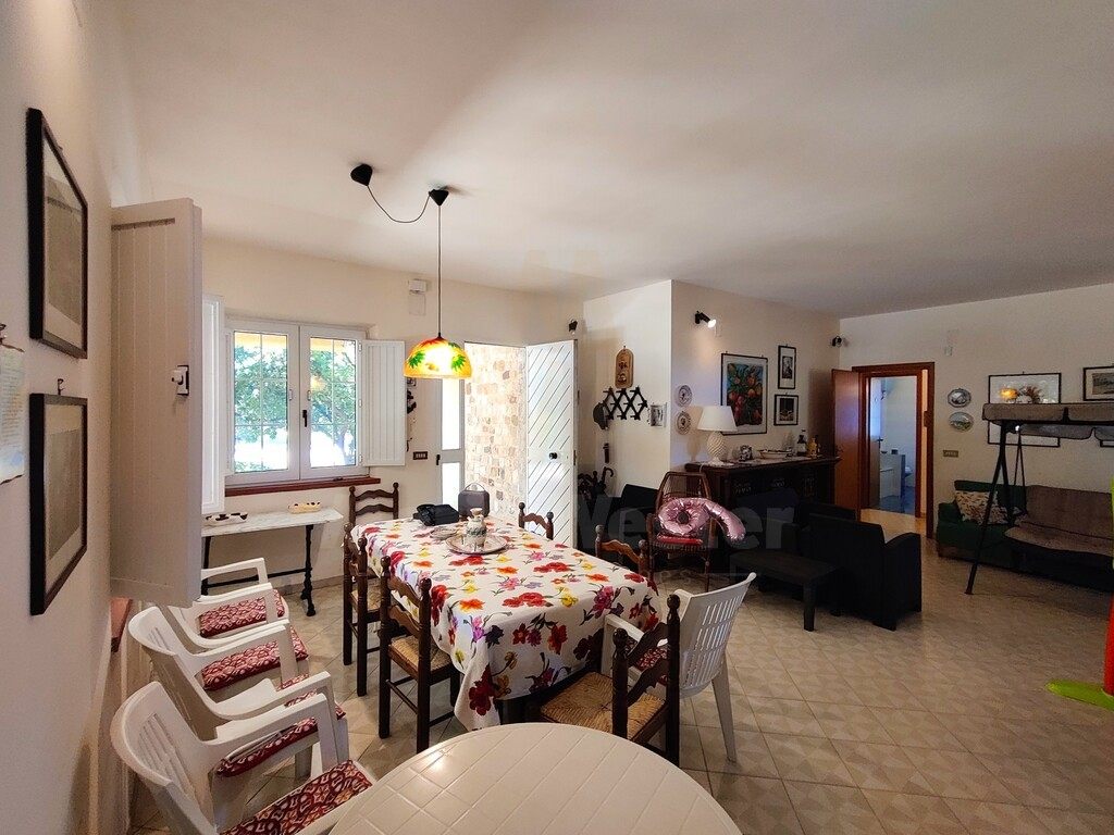 A lived-in dining room with a floral cloth, and a sitting room beyond