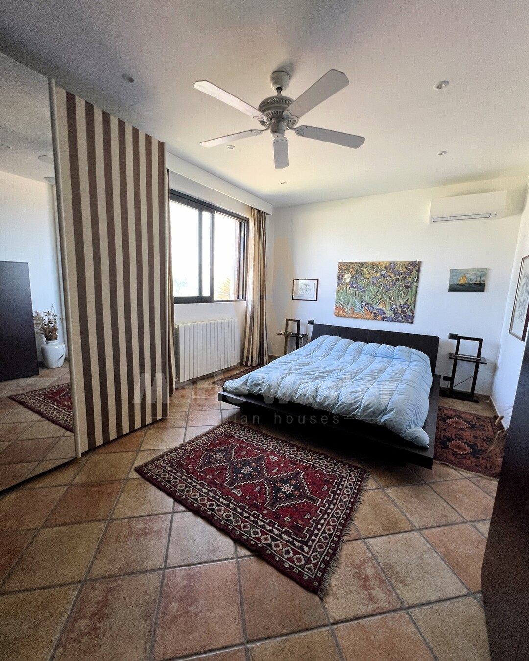 A downstairs bedroom with a striped screen, a ceiling fan, and an air conditioner