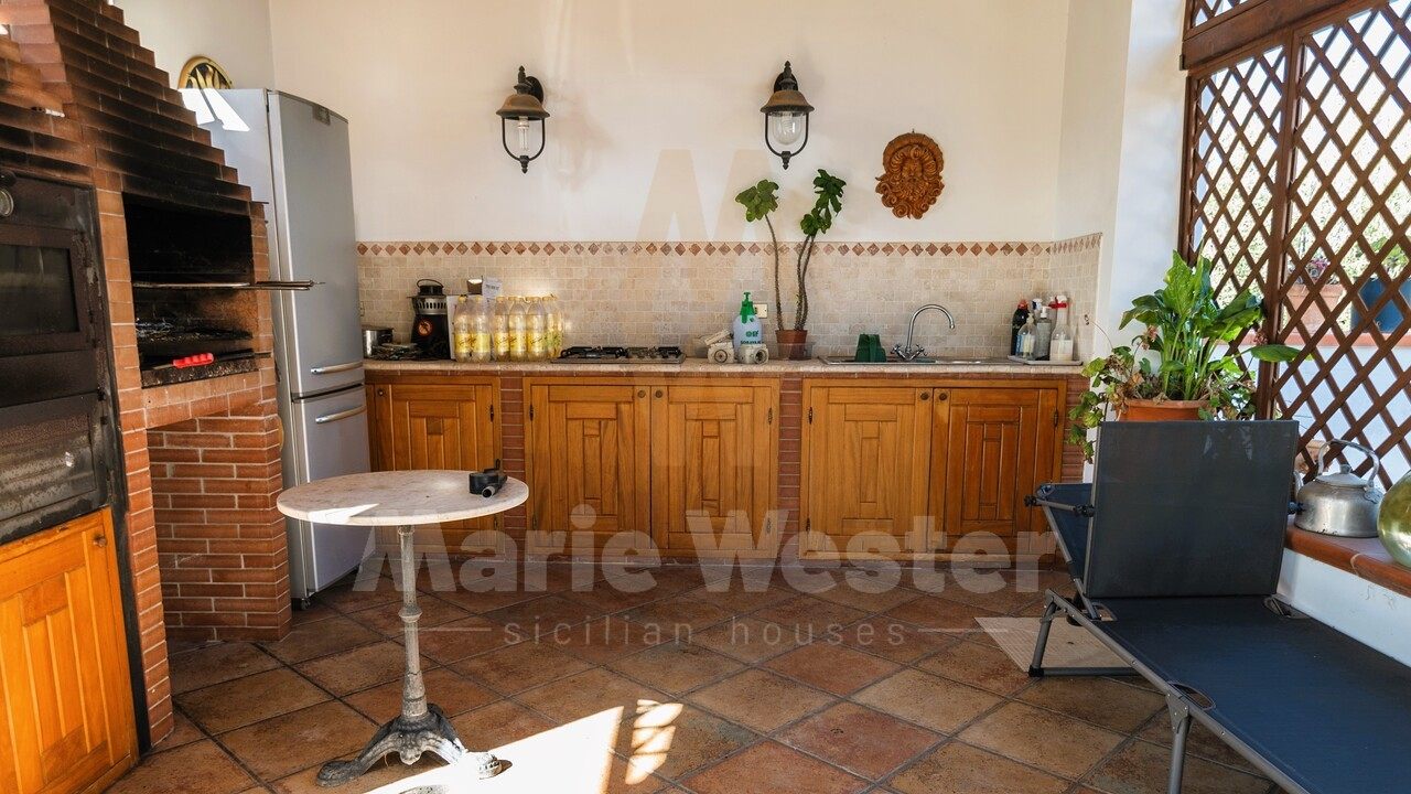 An outdoor kitchen with a brick oven, a fridge, and wood cabinets