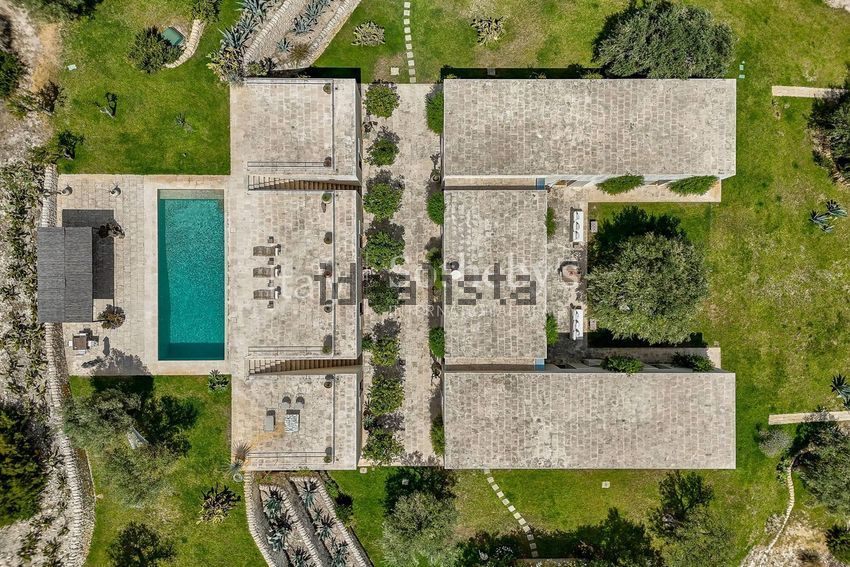 Overhead of a U of one-storey roofs around a court, with a rectangular pool to the left