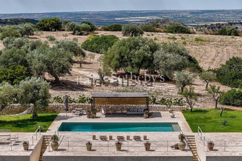 The pool seen from the roof, with dry olive hills and a shaded shelter beyond the terrace