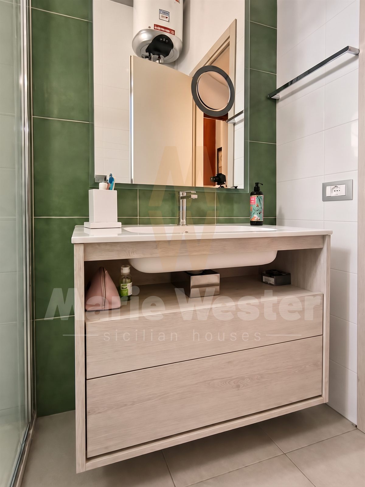 A small green-tiled bathroom with a water heater above the mirror