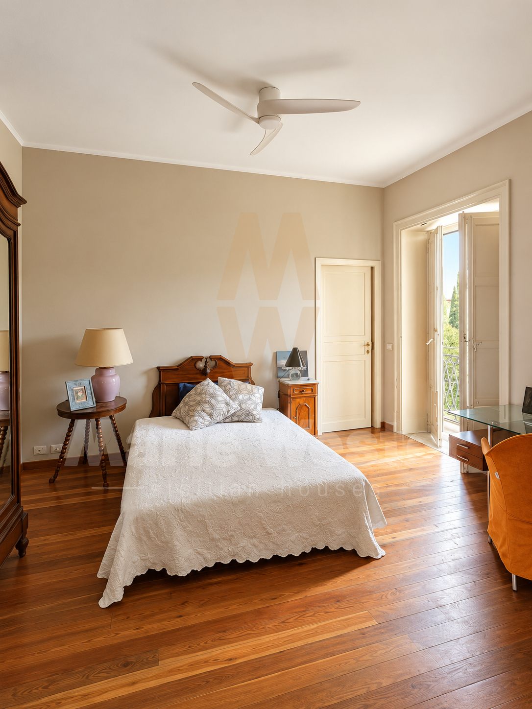 A bedroom with parquet, a ceiling fan, and doors onto a balcony