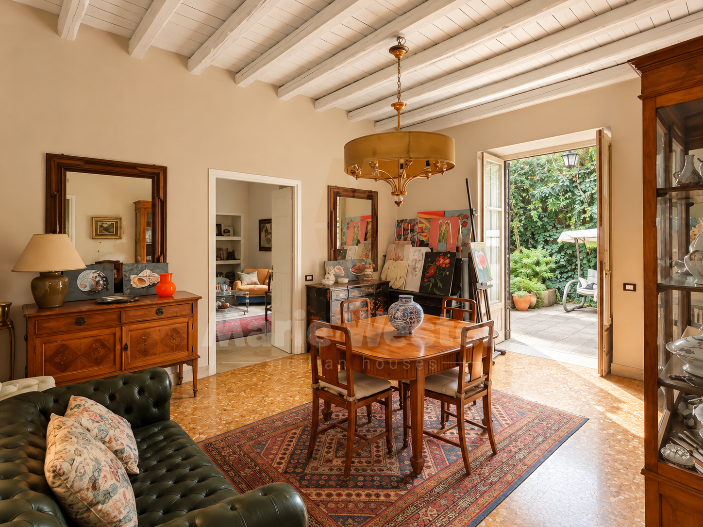 A dining room with beams and doors open onto the garden