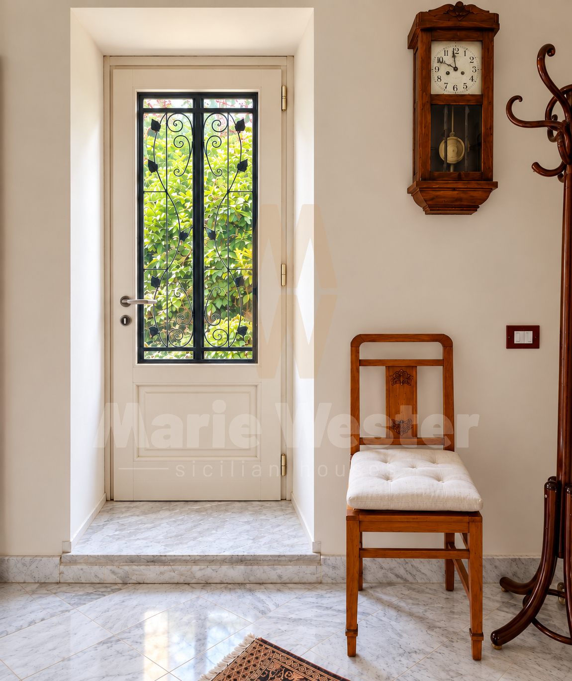 A hall with a wooden clock, a chair, and a glazed door into the garden