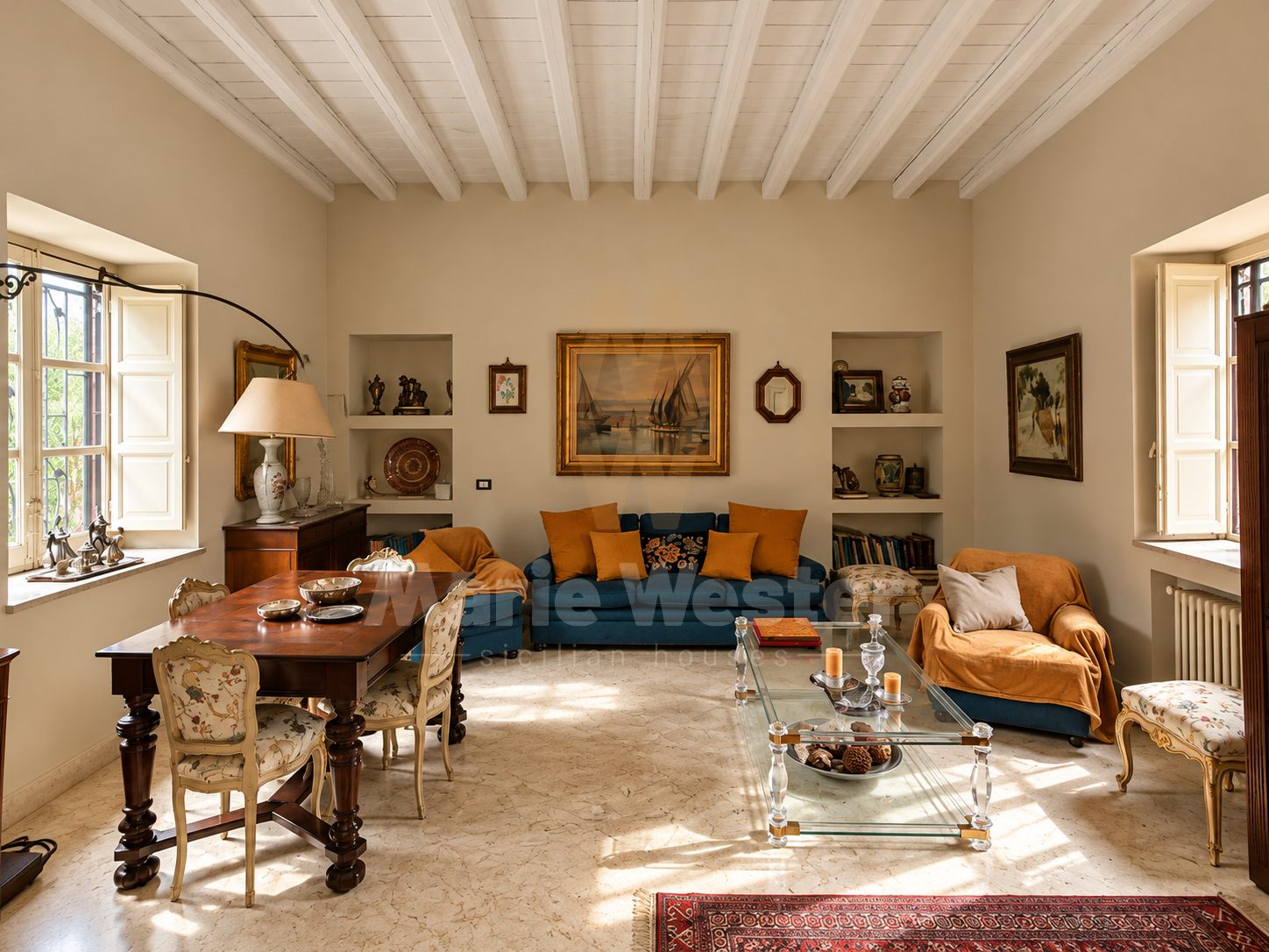 A furnished living room with a blue sofa, white beams, and shuttered windows