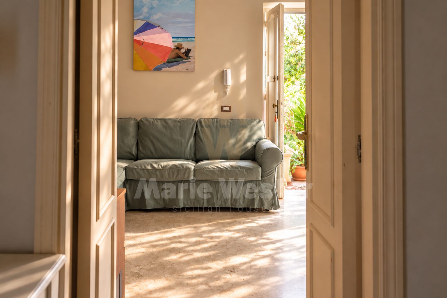 A sage sofa in a room that opens onto the garden