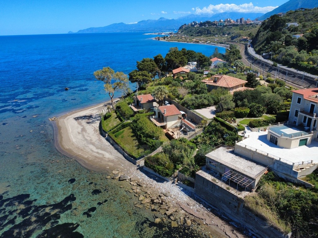 The villa above a small beach, with a stair through the garden and the railway behind