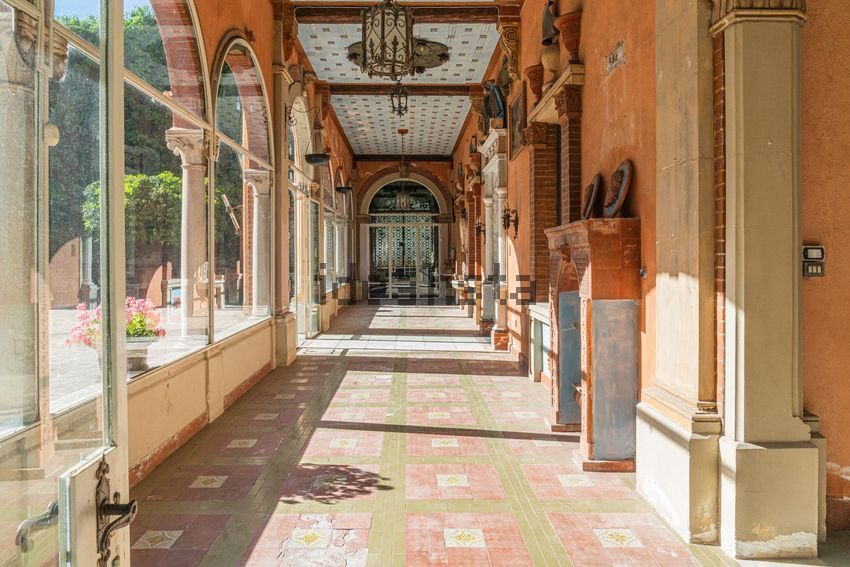 A long glazed loggia of arches with a patterned tile floor and a hanging lantern